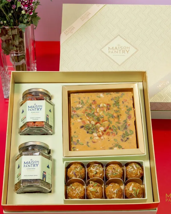 This premium gift hamper is a perfect example of my festive collection. It includes a box of my signature mithai, Panjiri Laddoos, and two jars of savory nuts, all presented in an elegant box ready for gifting.