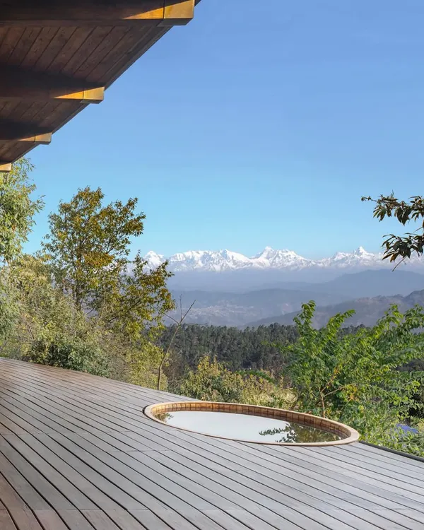 A Himalayan mountain home we designed, featuring a deck with a hot tub that looks out onto snow-capped peaks. The architecture is designed to be a viewing platform for the majestic landscape.
