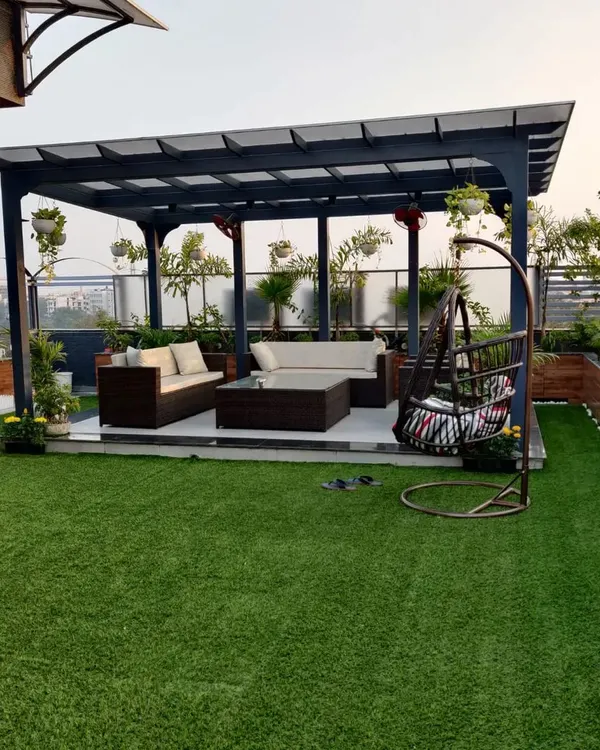 We designed this complete rooftop lounge, featuring a custom metal pergola for shade, comfortable outdoor seating, and artificial grass for a clean, low maintenance lawn. The space is framed by planters and hanging baskets to create a full garden atmosphere.
