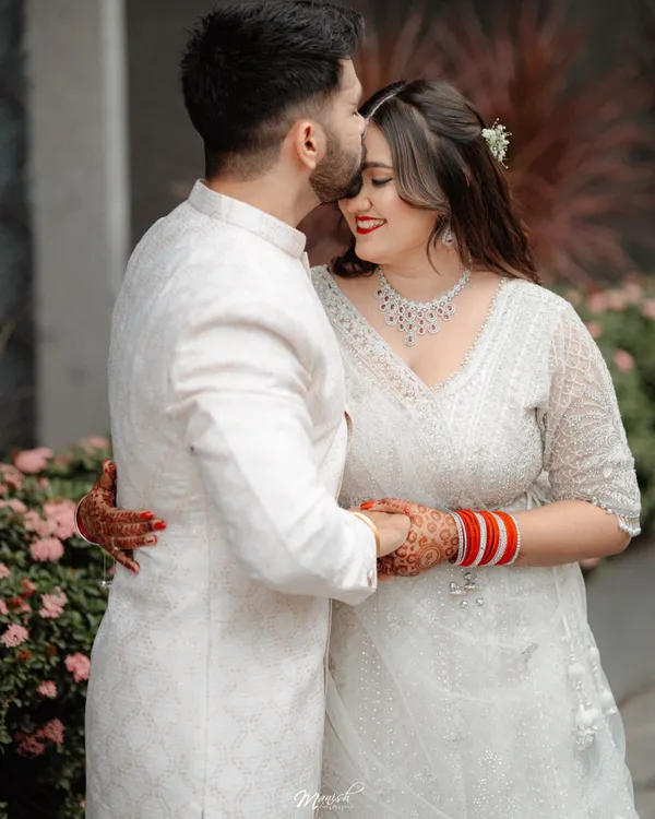 A tender forehead kiss, a classic and romantic moment from Utkarsh and Ruchika's engagement shoot. Their coordinated white outfits add to the elegance.