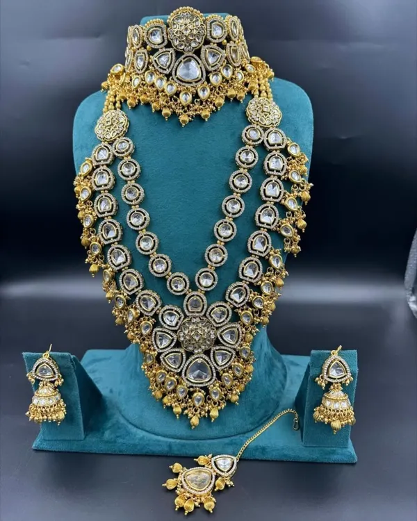 This is one of our grandest American diamond bridal sets available for rent. It features a heavy choker, a three-layer long necklace, and matching jhumka earrings and maang tikka for a truly unforgettable look.