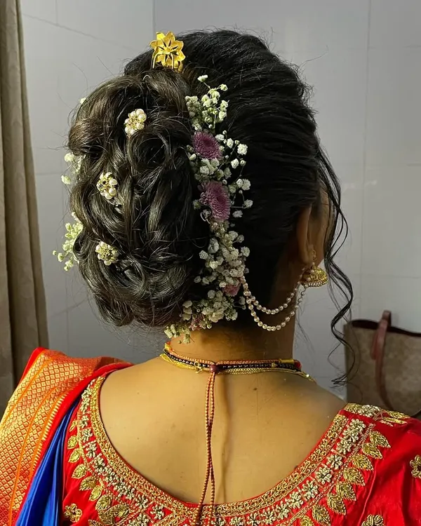 A detailed view of a beautiful textured bun for a Marathi bride. The hairstyle is adorned with delicate baby's breath and other small flowers for a romantic touch.
