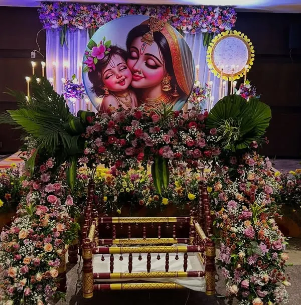 A full view of our floral cradle ceremony decoration. The traditional thottil is framed by an abundance of flowers, with a custom backdrop creating a divine atmosphere for the baby's first big event.