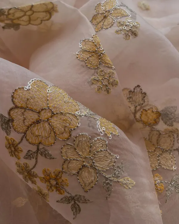 The rich gold threadwork on this blush pink organza creates a truly regal effect. The floral motifs are detailed with sequins, adding a touch of sparkle perfect for a wedding lehenga or a grand anarkali.