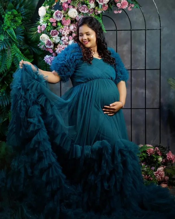This mom-to-be looks absolutely serene in our teal ruffled maternity gown. The gown's long trail and textured sleeves add a touch of drama, making it a popular choice for maternity photoshoots.