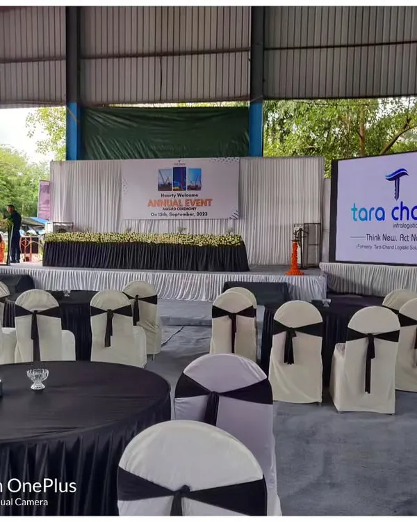 The stage and seating view for the Tara Chand InfraLogistics annual event. You can see the main stage with its floral decor and the large LED screen displaying the company's branding.