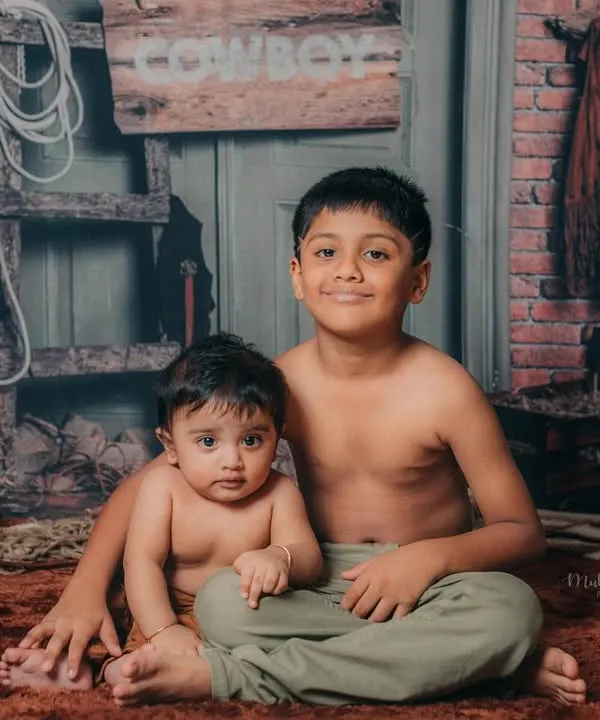 Big brother and little brother posing together in our rustic cowboy-themed studio setup. A perfect way to capture their bond.
