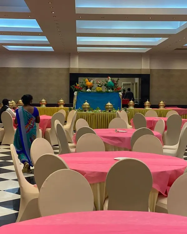 A spacious indoor wedding hall setup at CMA Palace, ready for guests. We arranged the seating with vibrant pink tablecloths to match the client's theme, ensuring the venue looked festive and welcoming.