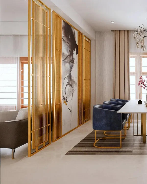 To create a sense of separation without closing off the space, I designed this elegant partition with gold-finished metal and abstract art. It beautifully frames the dining area, which features plush navy blue chairs and a sleek marble-top table for a contemporary, luxurious feel.
