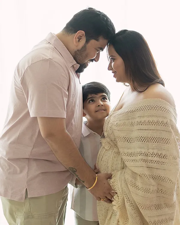 A beautiful moment of connection between expecting parents, with their son looking up at them. This image tells a story of a family eagerly awaiting their new arrival.