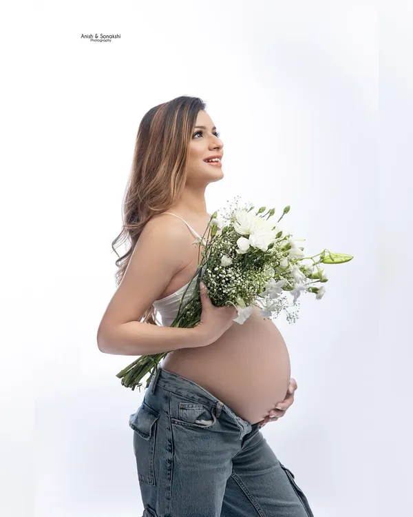 Blooming with joy. A simple, fresh, and modern maternity portrait with a beautiful bouquet of white flowers. The focus is all on that gorgeous baby bump and happy smile.