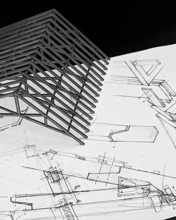 A physical model of a roof truss sits atop its corresponding architectural drawings. This juxtaposition of the tangible and the conceptual is at the heart of my design process, where ideas are constantly tested between different modes of representation.