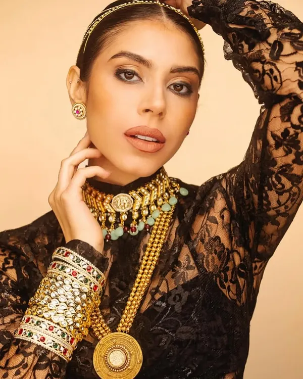 This look showcases how to style heavy, traditional gold jewellery with a modern twist. The intricate necklaces and bangles are paired with a contemporary black lace top for a bold, fusion statement.
