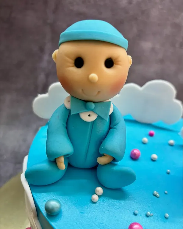 A close-up of the adorable baby boy topper for a gender reveal cake. I handcraft these little figures from fondant to make your surprise extra sweet.
