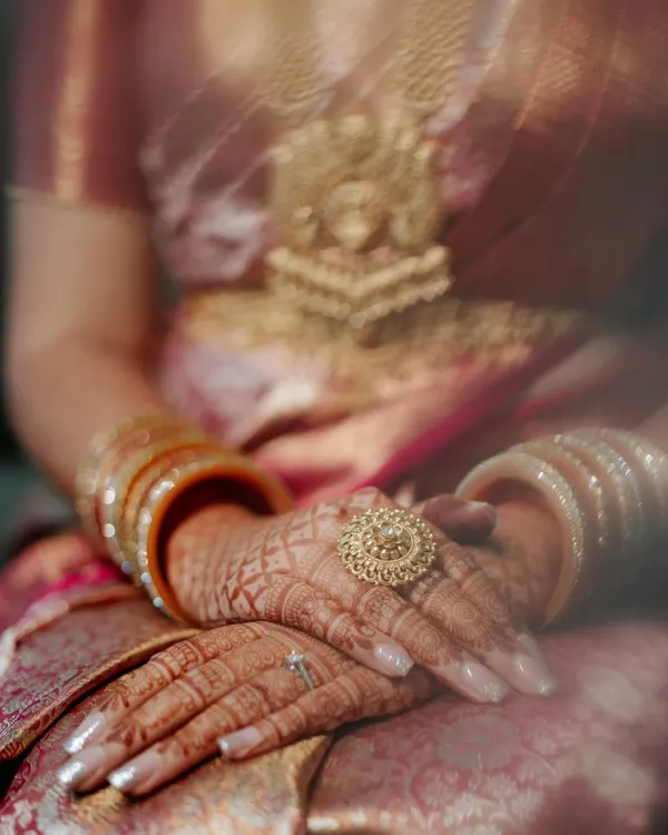 A close-up on the bride's hands, adorned with intricate henna and a stunning statement ring. This shot captures the beauty of South Indian bridal details and the quiet moments of anticipation.