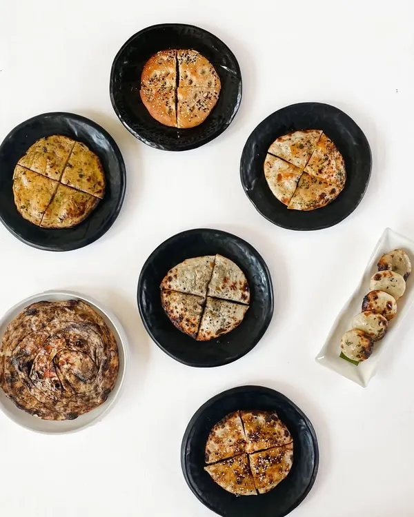 Our kulchas have a following of their own. This overhead shot shows a variety of our stuffed breads, from classic potato to inventive blue cheese, each quartered and ready for sharing.