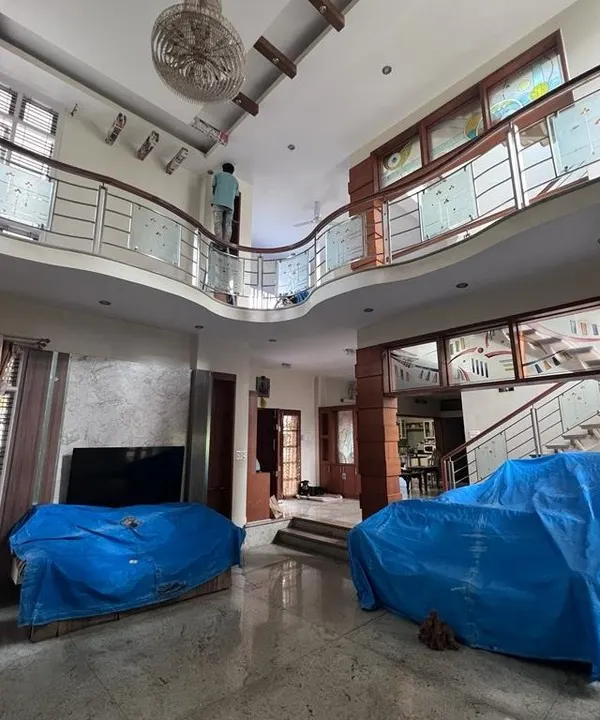 This is the beginning of a transformation in a large duplex home. You can see how we meticulously cover all furniture and flooring with protective sheets before starting any painting work on the high walls and ceilings.