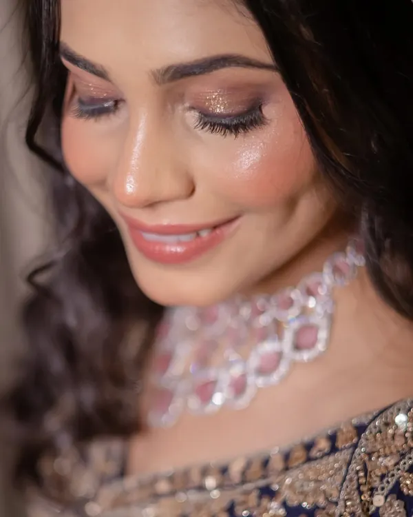 A close-up of a glamorous Sangeet makeup look. The focus is on the shimmery, smokey eye makeup and glossy nude lips, perfect for an evening of celebration.