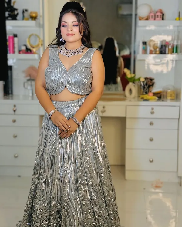 A full-length view of a dazzling silver sequin lehenga. The wave-like pattern of the sequins creates a fluid, glamorous look perfect for an engagement or cocktail night.