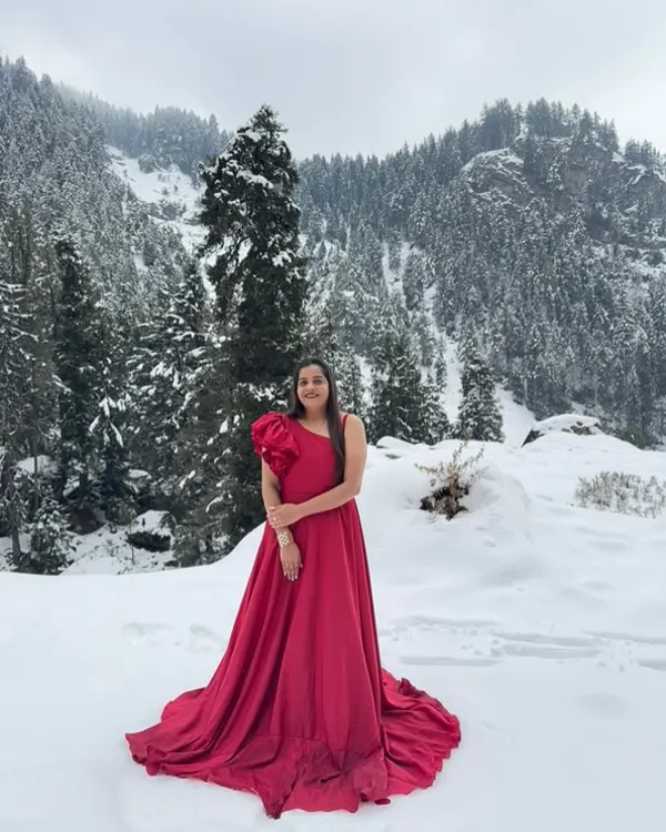 Make your pre-wedding shoot epic with one of our rental gowns. This vibrant red one-shoulder gown with a ruffled sleeve provides a stunning pop of color, especially in a scenic location like this snowy landscape.
