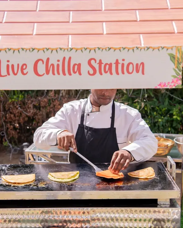 A chef preparing fresh chilla at a live station. Guests love watching their food being made, and it ensures every serving is hot, fresh, and made to their preference.
