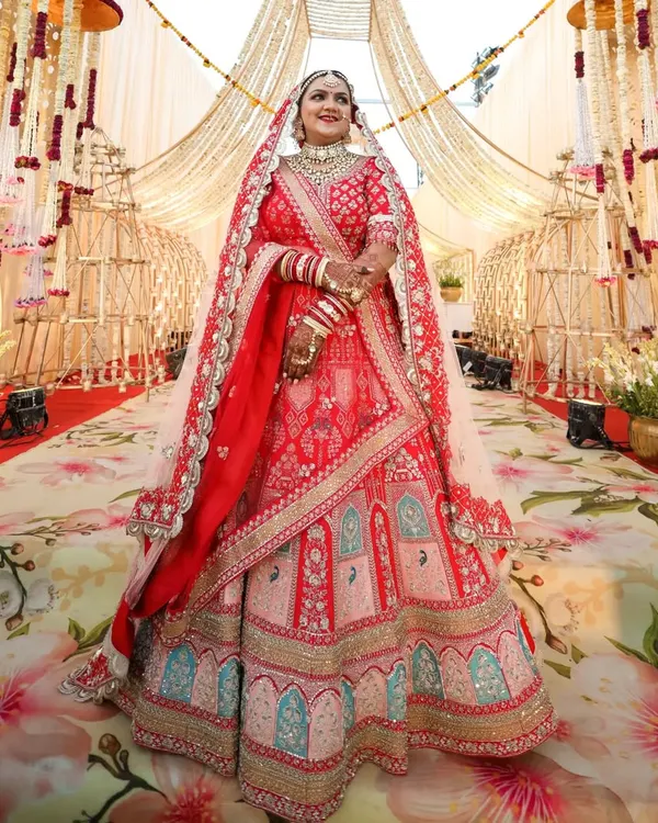 A full view of this breathtaking Rajasthani bride. Her makeup was designed to be flawless from every angle, with classic red lips and defined eyes that stood out against her elaborate red bridal lehenga.