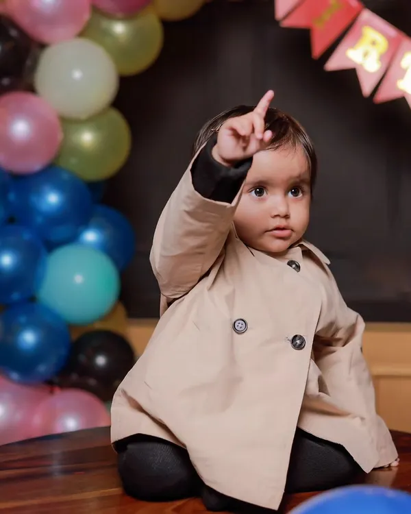 The birthday boy, Vasuki, pointing up as if to say "I'm one!". I focus on capturing these fleeting gestures and expressions that make for unforgettable first birthday photos.