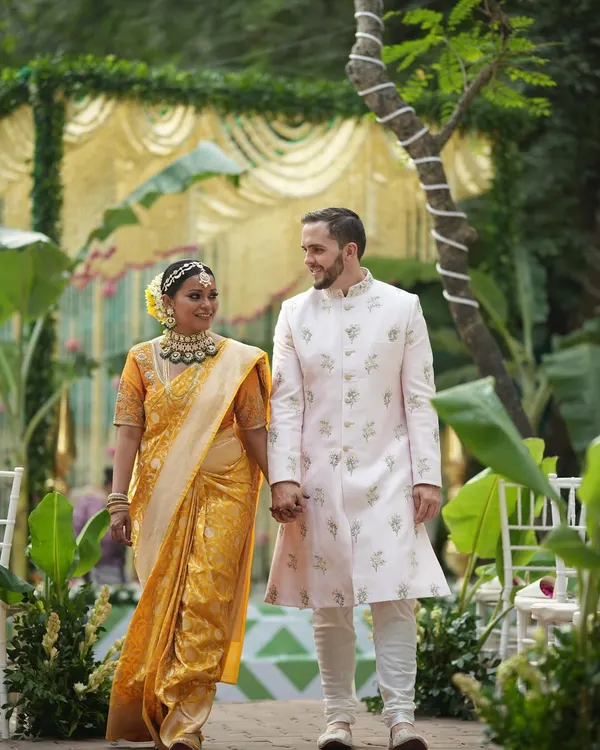For Sam and Matt's wedding in Pune, we blended her South Indian roots with his Western background. Here they are, taking their first walk as a married couple, with the bride in a stunning traditional yellow saree and the groom in a classic embroidered sherwani.