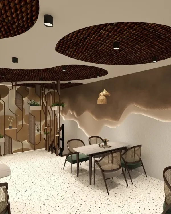 The main dining area of this Haldwani cafe features custom-designed ceiling panels with woven inserts, creating a unique, organic canopy. The space is furnished with cane-backed chairs and marble-topped tables on a bright terrazzo floor.
