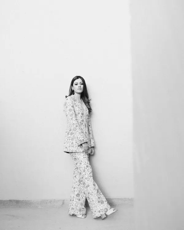 A striking, minimalist black and white portrait of the bride, Mouli, against a clean wall, her modern Sabyasachi pantsuit creating a powerful silhouette.