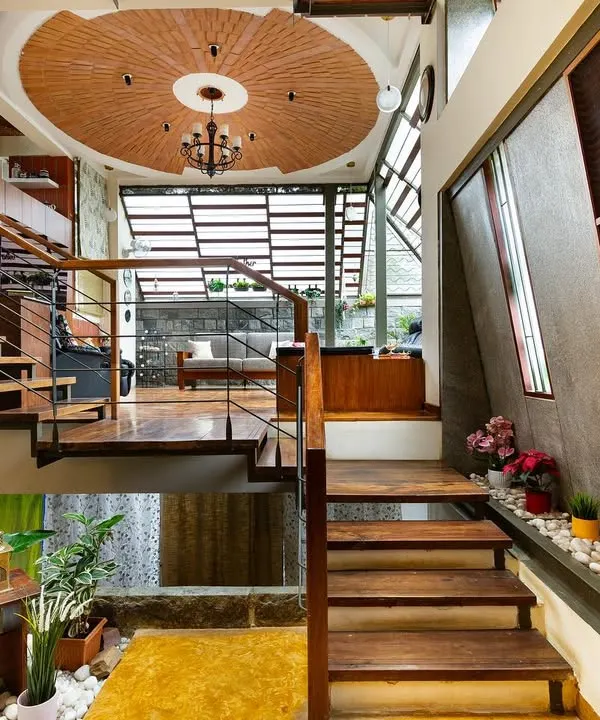 This view captures the heart of a multi-level home I designed, where life unfolds across interconnected spaces. The open staircase, warm wooden flooring, and a unique terracotta disc ceiling are all tied together by an abundance of natural light and indoor greenery, creating a home that feels both expansive and intimate.