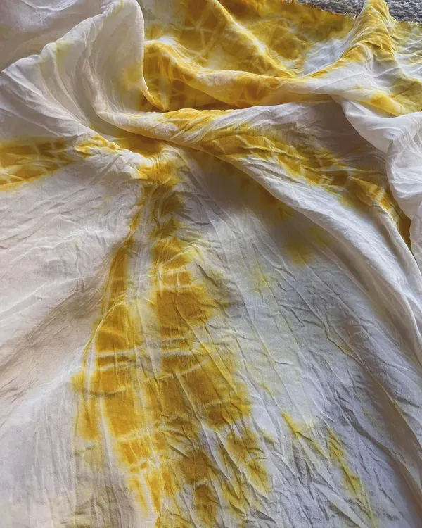 This beautiful yellow Mulberry Silk fabric was dyed with turmeric using a 10% mordant to ensure the color stays vibrant forever with easy care. The tie-dye technique creates a stunning, sunburst-like pattern.