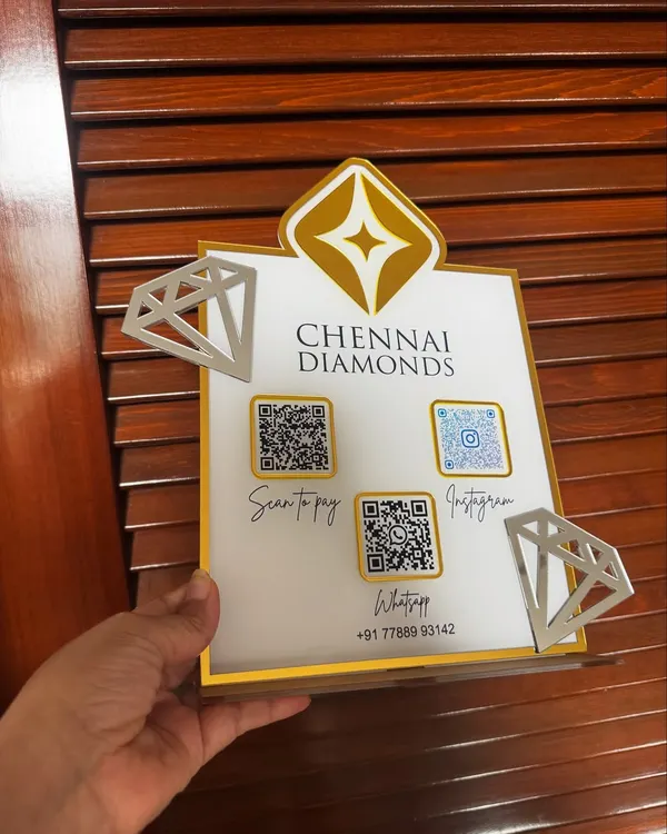 A hand-held view of the custom QR stand for Chennai Diamonds, showing the crisp engraving and the 3D effect of the logo and diamond cutouts.