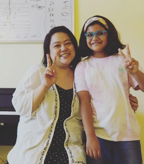 A happy moment with a student after a productive vocal session. The whiteboard behind us shows some of the music theory fundamentals we cover, like solfege and notation, which are essential for every singer and musician.