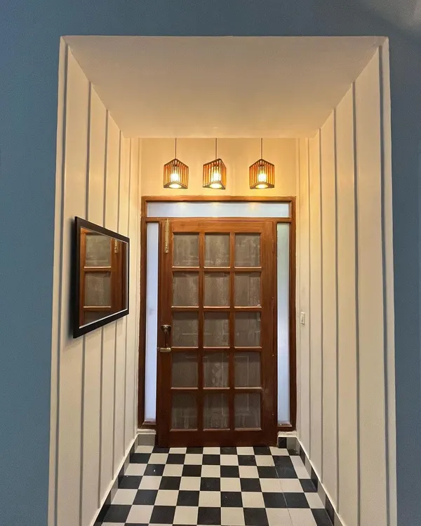 This entryway transformation captures our love for timeless design. We replaced a plain entrance with classic checkerboard flooring, a beautiful teak wood door with frosted glass panels, and warm pendant lighting. The result is a welcoming and elegant first impression that sets the tone for the rest of the home.