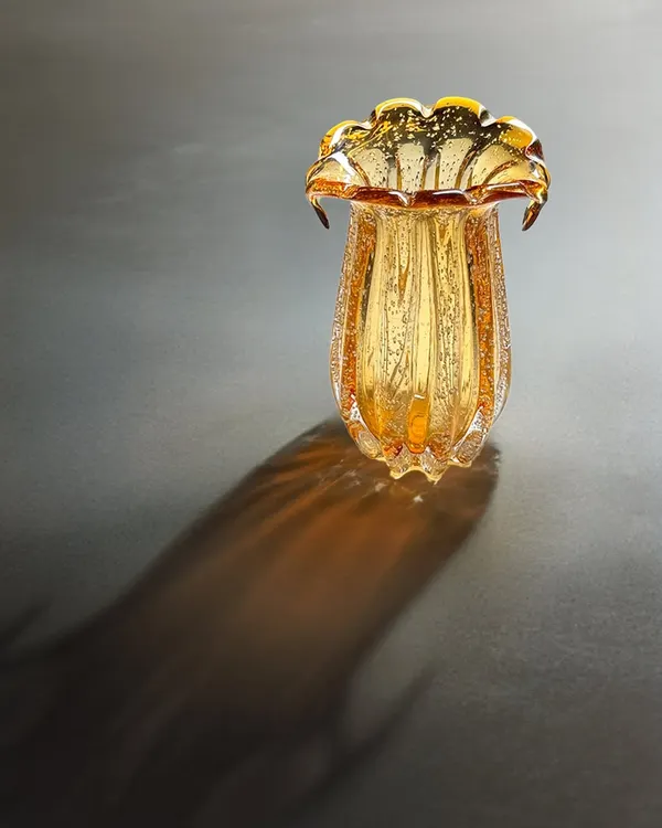 Where light dances on glass. This hand-blown amber glass vase is designed to catch the light, casting beautiful shadows and becoming an art piece in its own right.
