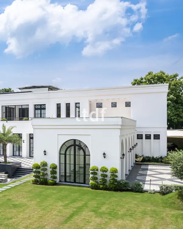 This view of the farmhouse highlights its refined elegance, with large French-style arched windows that flood the interior with natural light. The design balances contemporary simplicity with the grandeur of traditional architectural forms.