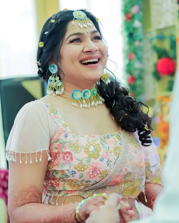 A close-up of the bride's happy face during her Haldi ceremony. The makeup is minimal and fresh, with a focus on rosy cheeks and a bright smile to match the festive vibe.