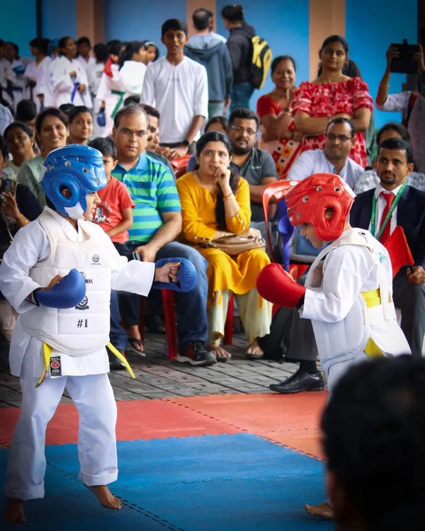 Young competitors engage in a Kumite match while parents and spectators watch. Our championships are family-friendly events that celebrate the hard work and courage of every participant.