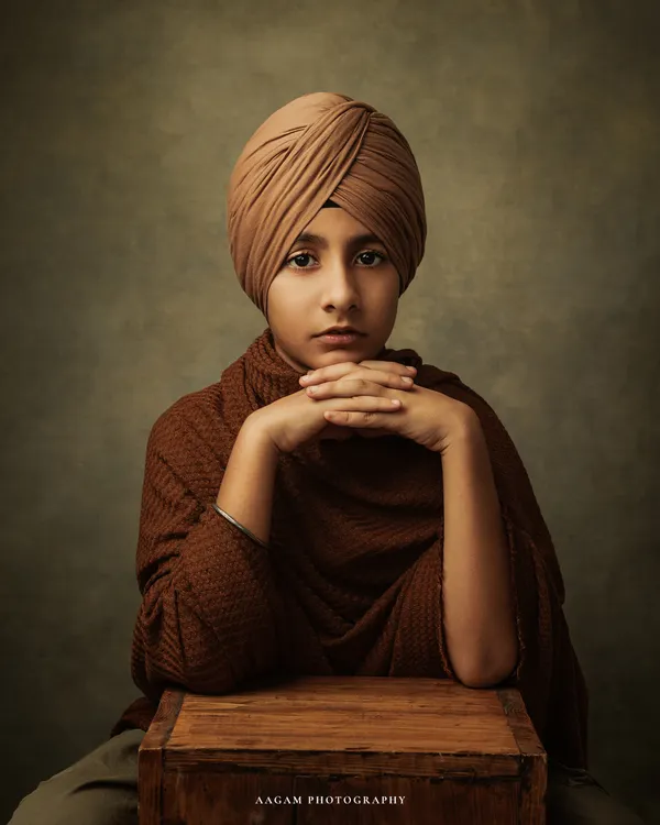 A powerful and soulful fine art portrait of a young boy. His direct gaze and the classic, painterly style create a timeless image that feels like it belongs in a gallery.