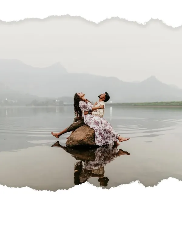 An epic shot of the couple relaxing on a rock in the middle of a serene lake, with the mountains of the ghats in the background.