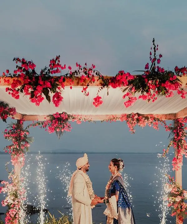 I believe some moments are as endless as the ocean. Here, under a canopy of bougainvillea and with sparks celebrating their union, the couple begins their beautiful journey against the serene backdrop of a Goan sea.