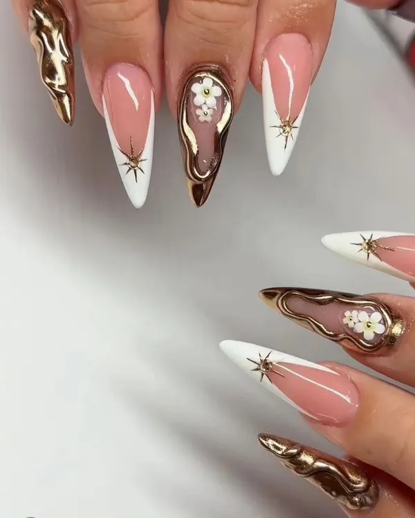A high-fashion, mixed-media set featuring stiletto nails with white French tips, 3D gold chrome, and delicate hand-painted flowers.
