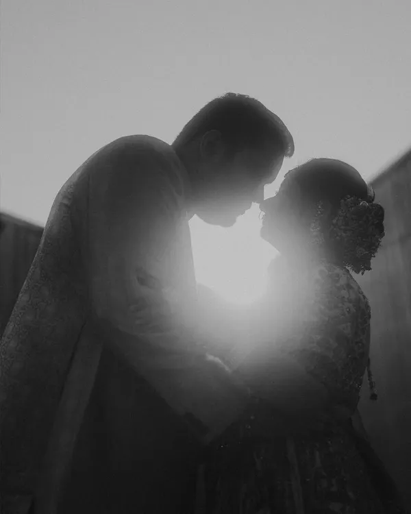 A silhouette against the sun, a moment of pure connection captured in black and white. This is about the highlights and shadows of love, creating an iconic and timeless couple portrait.