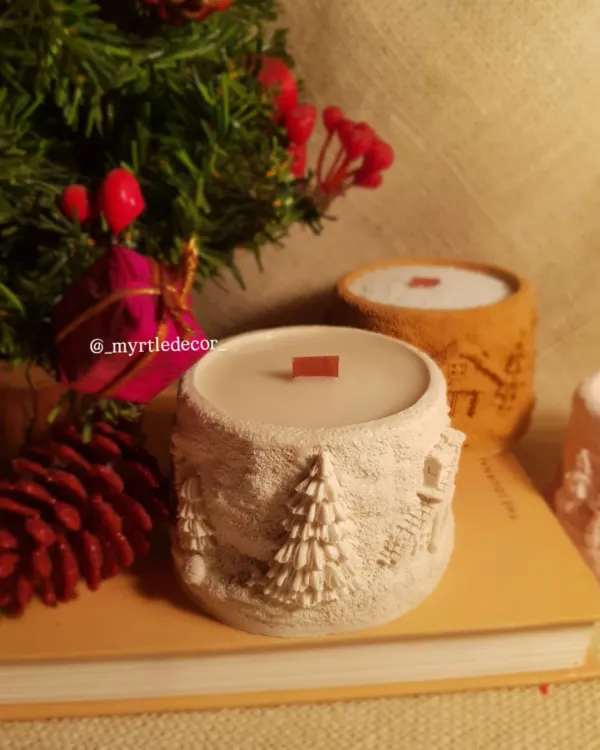 Our 'Winter Lights' Jar Candle, featuring a cozy, textured winter cabin scene. We make the jar from Jesmonite and fill it with 100% soy wax, creating a piece that brings warmth and a season in a flame.