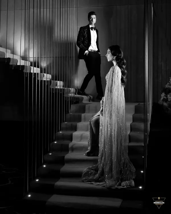 A dramatic black and white portrait of the couple on a staircase. This shot is all about style, mood, and creating a cinematic, high-fashion look for their engagement.