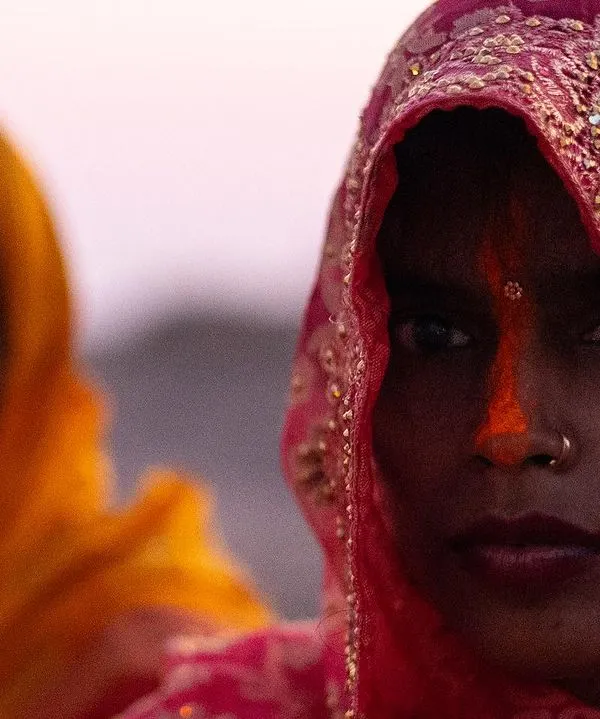 A close portrait of a woman during Chhath Puja in Bihar, her direct gaze and the traditional sindoor creating a powerful image of faith.