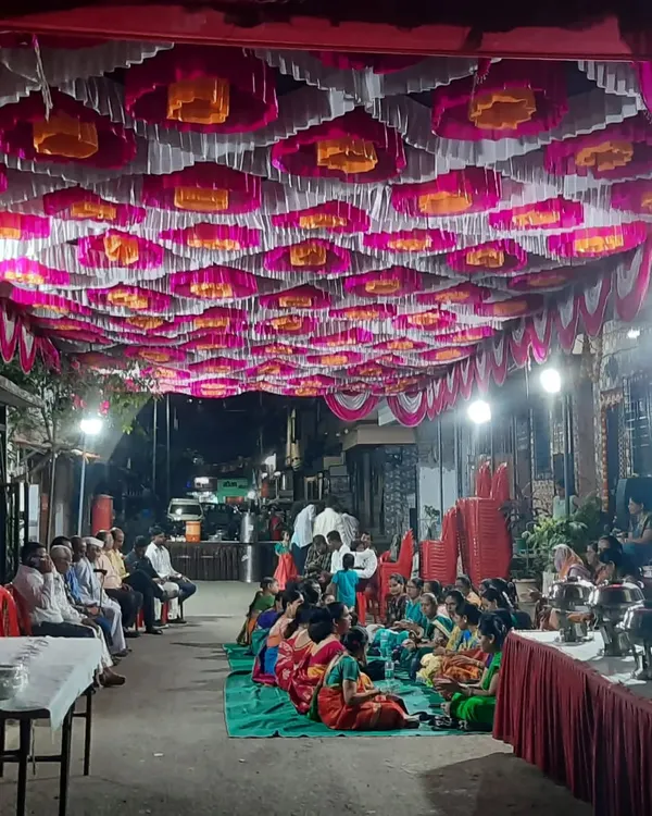 A large gathering seated on the floor inside a pandal. I provide carpets (galicha) and manage the complete seating arrangement for community dining or functions.