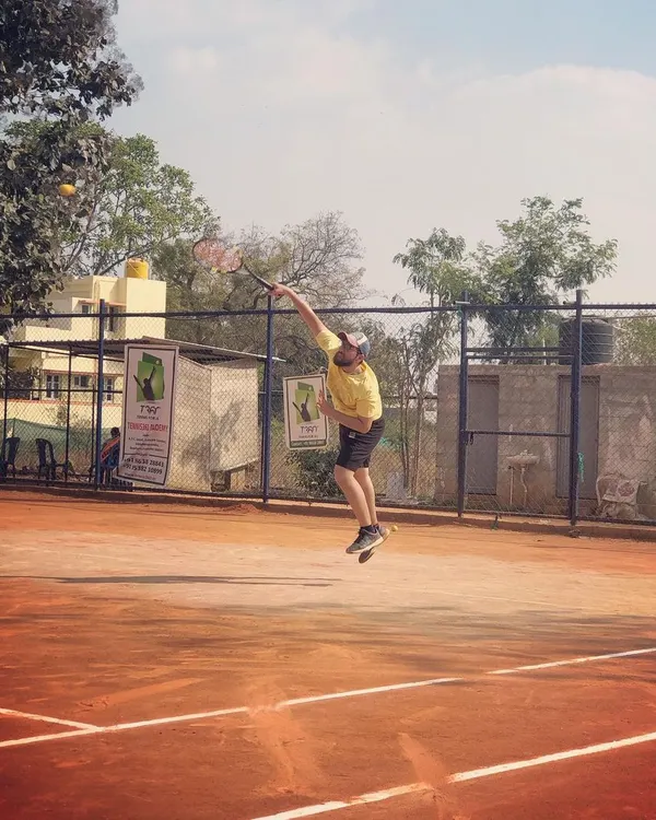 An adult male player leaps into a powerful serve during the Tennis360 Men's Open Tour.
