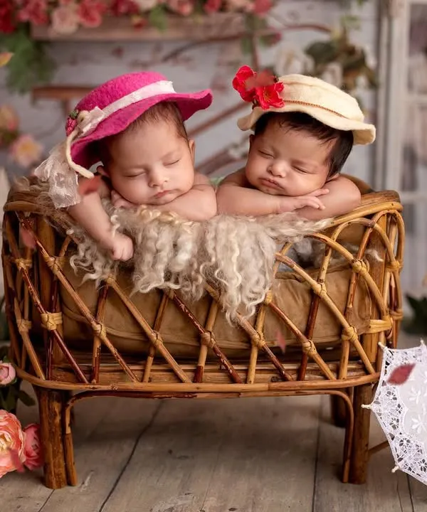 When a mom requested a Bridgerton theme for her twins, I was so excited! Look at these two little debutantes with their tiny hats, sleeping in a vintage-style bassinet surrounded by flowers.